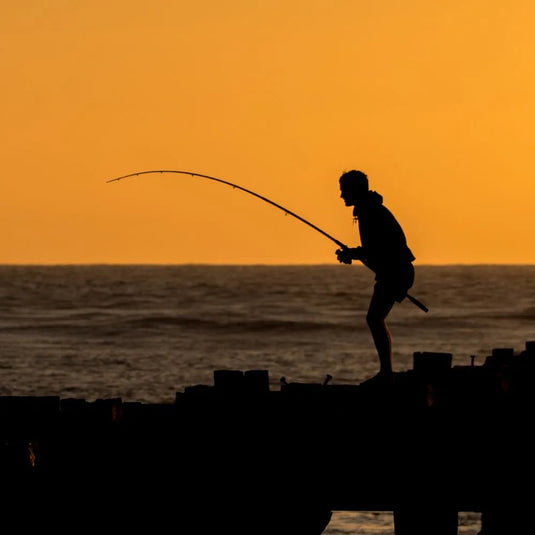 Angler bei Sonnenuntergang am Wasser